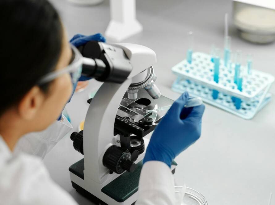 Scientist conducting research in a lab using a microscope and dropper.